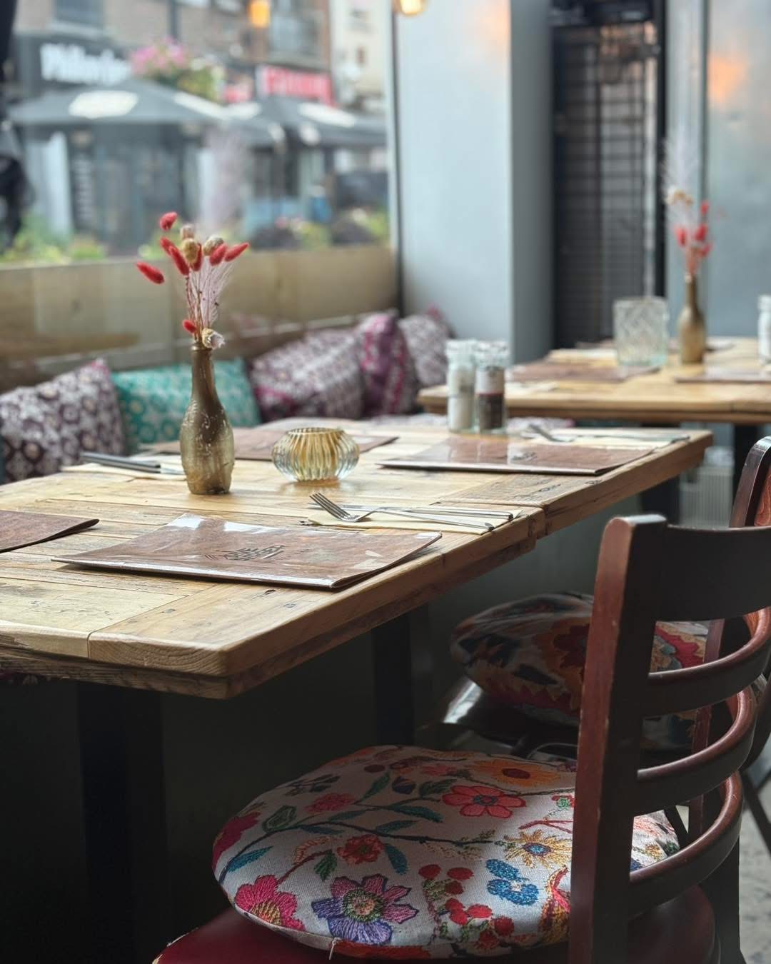 Table en bois avec fleurs séchées et coussins brodés près de la fenêtre
